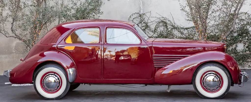 Interior dashboard of a 1937 Cord 810 with engine-turned aluminum panel and edge-lit gauges, evoking 1930s luxury