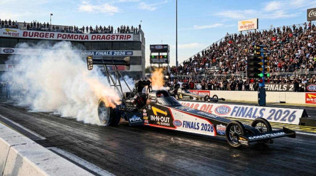 A Top Fuel dragster launching from the starting line in a cloud of tire smoke at In-N-Out Burger Pomona Dragstrip during the NHRA Finals 2026 in California